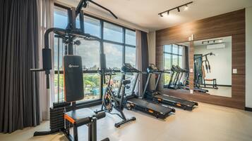A gym with exercise equipment, large windows, and a mirror.