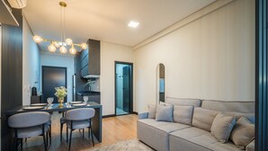 Un salon moderne avec un canapé, une table à manger et des chaises, un lustre et un miroir.