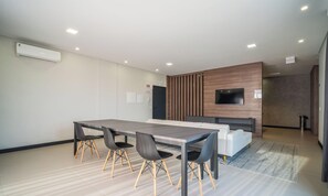 Een moderne vergaderruimte met een lange tafel, stoelen, een flatscreen-televisie en een houten accentmuur.