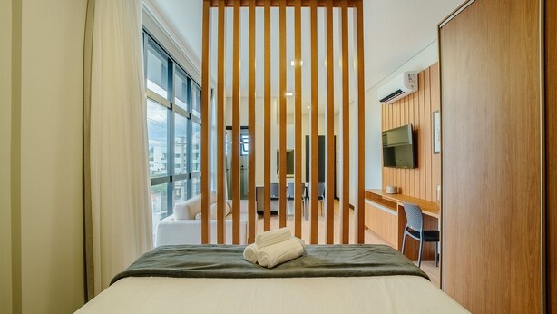 Une chambre d’hôtel avec un lit, un téléviseur fixé au mur et une vue sur l’extérieur.