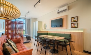 A modern hotel room with a dining area, a sofa, a TV, and artwork on the wall. - Complete Stay Just 550 Meters From Praia dos Ingleses - Ldus (Florianópolis)