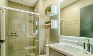 Een moderne badkamer met een douchecabine van glas, een wit wastafelmeubel en een spiegel erboven.