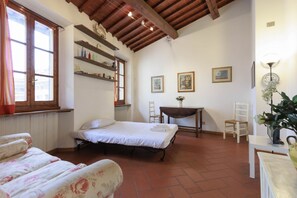 A room with a bed, a chair, a table, shelves with bottles, and framed pictures on the wall. - Savonarola Loft - Florence  (Firenze)