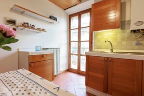 A compact kitchen with wooden cabinets, a white countertop, and a window with a view. - Savonarola Loft - Florence  (Firenze)