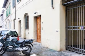 A motorcycle parked in front of a building with a wooden door and a metal gate. - Savonarola Loft - Florence  (Firenze)
