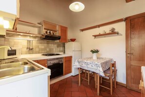 A compact kitchen with a sink, stove, oven, and a dining table with chairs. - Savonarola Loft - Florence  (Firenze)