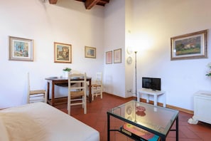 A room with a bed, a dining table with chairs, a TV on a stand, and framed pictures on the walls. - Savonarola Loft - Florence  (Firenze)