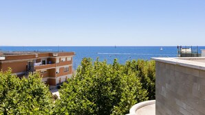 A coastal view with buildings, a clear sky, and a distant sailboat. - BDC - Aurelia Seaview! (Santa Marinella)