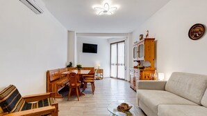 A modern living room with a sofa, a glass coffee table, and a dining area with wooden furniture. - BDC - Aurelia Seaview! (Santa Marinella)