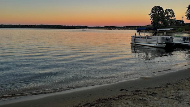 Un lago tranquillo al tramonto con un molo e una barca.