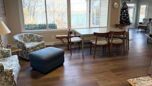 Un soggiorno spazioso con pavimento in legno, un tavolo da pranzo con sedie, un pouf blu e poltrone a fantasia floreale.