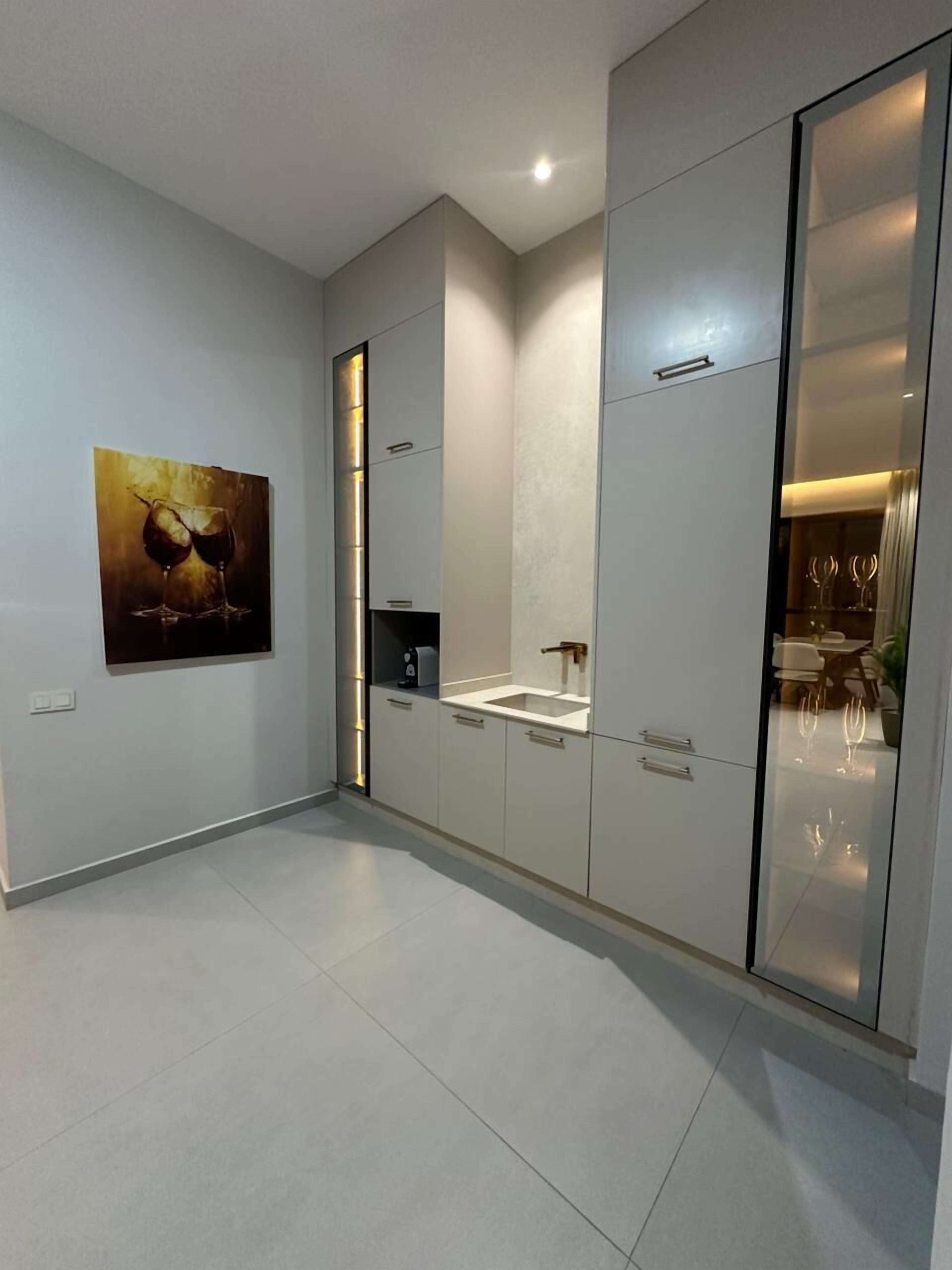 A modern kitchen with white cabinets, a built-in oven, and a large window.