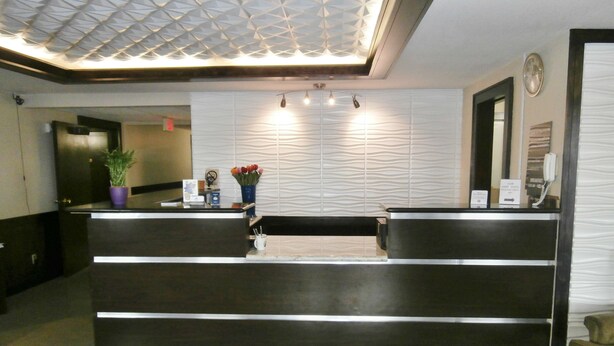 A reception desk with a modern design, a clock on the wall, and a potted plant.