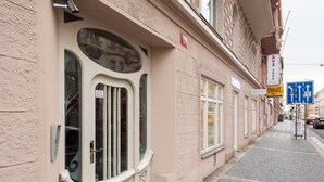 Un bâtiment doté d’une grande fenêtre en arc de cercle, d’une enseigne indiquant une fourchette de prix de 1200, et d’un panneau de signalisation bleu placé sur le trottoir.