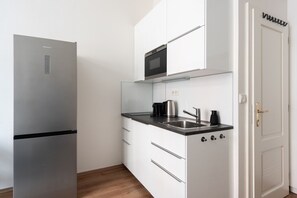 A compact kitchen with a stainless steel refrigerator, a microwave, a sink, and a coffee maker. - Stylish Riverside Studio | City Center, Park & Smart TV by EasyBNB Premium (Prague)