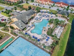 An aerial view of a resort with a large swimming pool, sun loungers, and a tennis court. - 4BR Paradise Palms Townhome, Heated Pool (Kissimmee)
