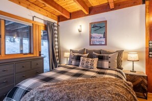 Ein Schlafzimmer mit karierter Bettdecke, einem Fellüberwurf und einem Poster von Squaw Valley.