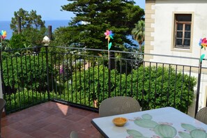 Un balcon avec une table et des chaises, une vue sur la mer et des décorations en forme de moulins à vent miniatures.