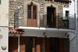 A stone building with a balcony, wooden shutters, and a tiled roof. - Prickly Pear Appartament (SANTO STEFANO DI CAMASTRA - ME)