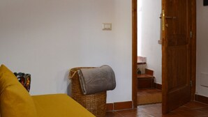 Ein Zimmer mit einem Bett, einem Korbwannen-Korb mit einer Decke, einer Holztür und einer kleinen Treppe, die zu einem Badezimmer führt.