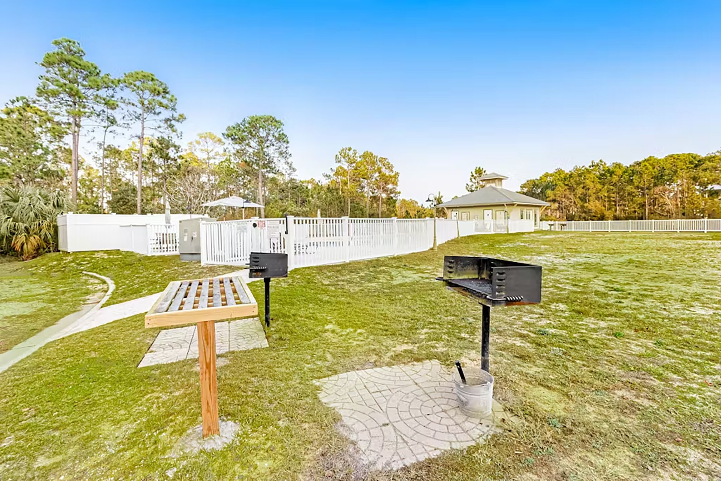 A grassy outdoor area with a wooden bench, a trash bin, and a mailbox.