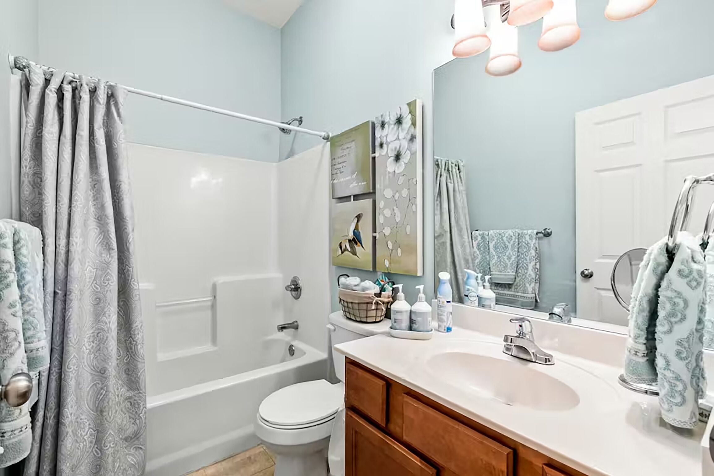 A bathroom with a bathtub, toilet, vanity, and a large mirror.