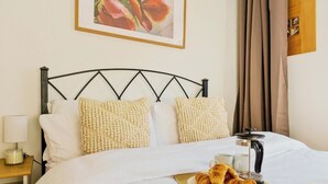 A neatly made bed with white linens and two textured pillows, a bedside table with a lamp, and a breakfast tray with croissants and a coffee pot. - 2BR Docks View Flat With Free Parking Terrace Fast WiFi TV BBQ PrivateGarden (London)