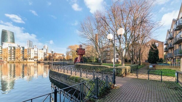 A riverside walkway with a metal railing, a lamp post, and a statue. - 2BR Docks View Flat With Free Parking Terrace Fast WiFi TV BBQ PrivateGarden (London)