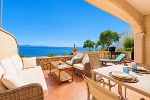 A terrace with outdoor furniture, a table, and a view of the sea. - Villa Casa Faro - Four Bedroom Villa, Sleeps 8 (Mallorca)