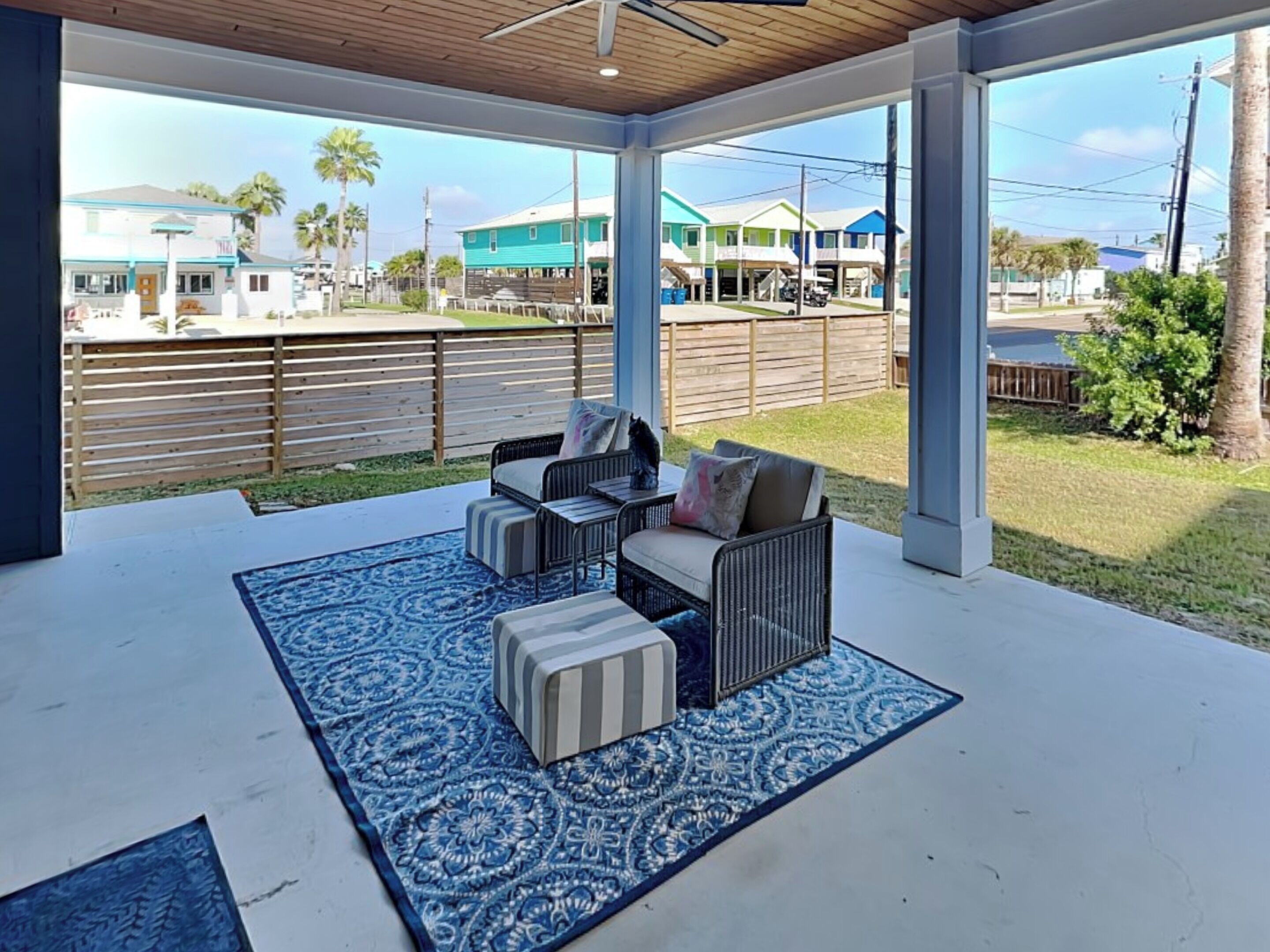 An outdoor patio with a blue patterned rug, a sofa, and a chair.