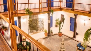 Un patio de varios niveles con barandillas de madera, plantas en macetas y una fuente.
