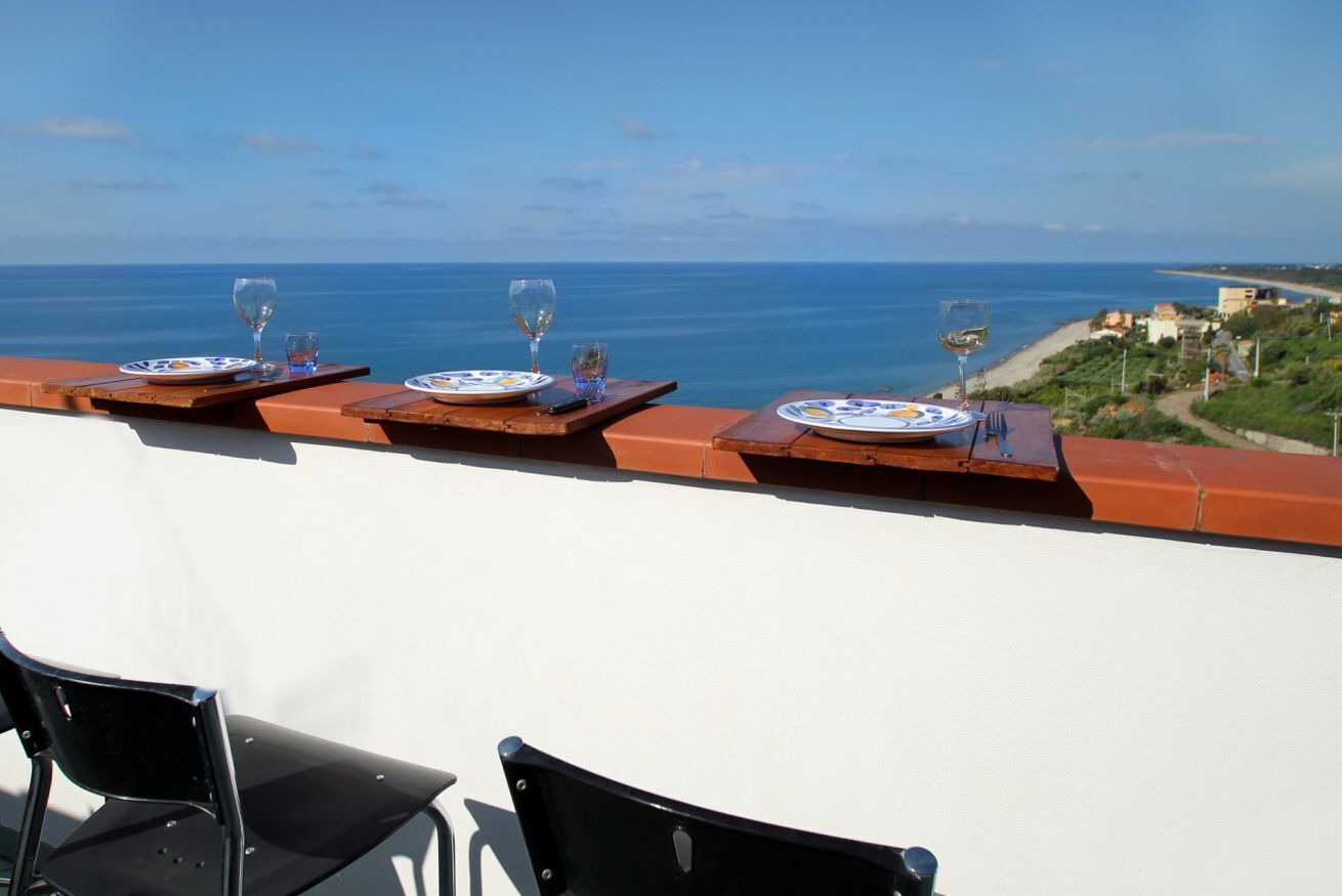 Ein Balkon mit Essplätzen und Blick auf die Küste.