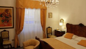 Una camera d'albergo con un letto grande, due sedie, un comodino con una lampada e un lampadario.