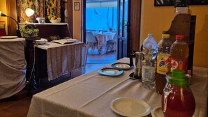 A dining area with a table set for two, a view of the outdoors, and a painting on the wall. - Turquoise fairy family suite (Collodi)