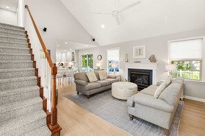 Ein geräumiges Wohnzimmer mit Kamin, einer Treppe und einem Essbereich.