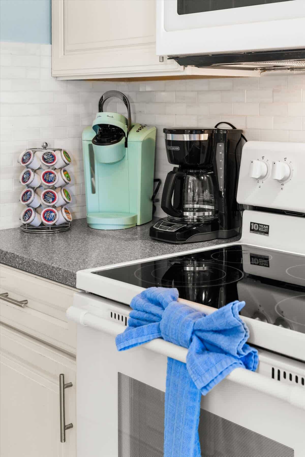 A kitchen with a microwave, coffee maker, and kettle on the counter.