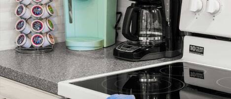 Une cuisine équipée d’un four à micro-ondes, d’une machine à café et d’une bouilloire, le tout posé sur le plan de travail.