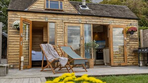 A wooden cabin with a deck, a lounge chair, and a fireplace. - Tinywood One, dog friendly with hot tub in Warwick (Long Itchington)