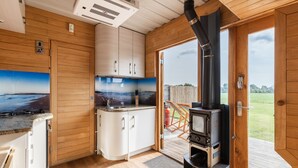 A compact kitchen with wooden cabinets, a built-in stove, and a view of the outdoors. - Tinywood One, dog friendly with hot tub in Warwick (Long Itchington)