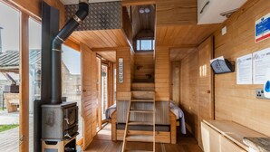 A wooden cabin interior with a wood stove, a loft bed, and a ladder to the loft. - Tinywood One, dog friendly with hot tub in Warwick (Long Itchington)