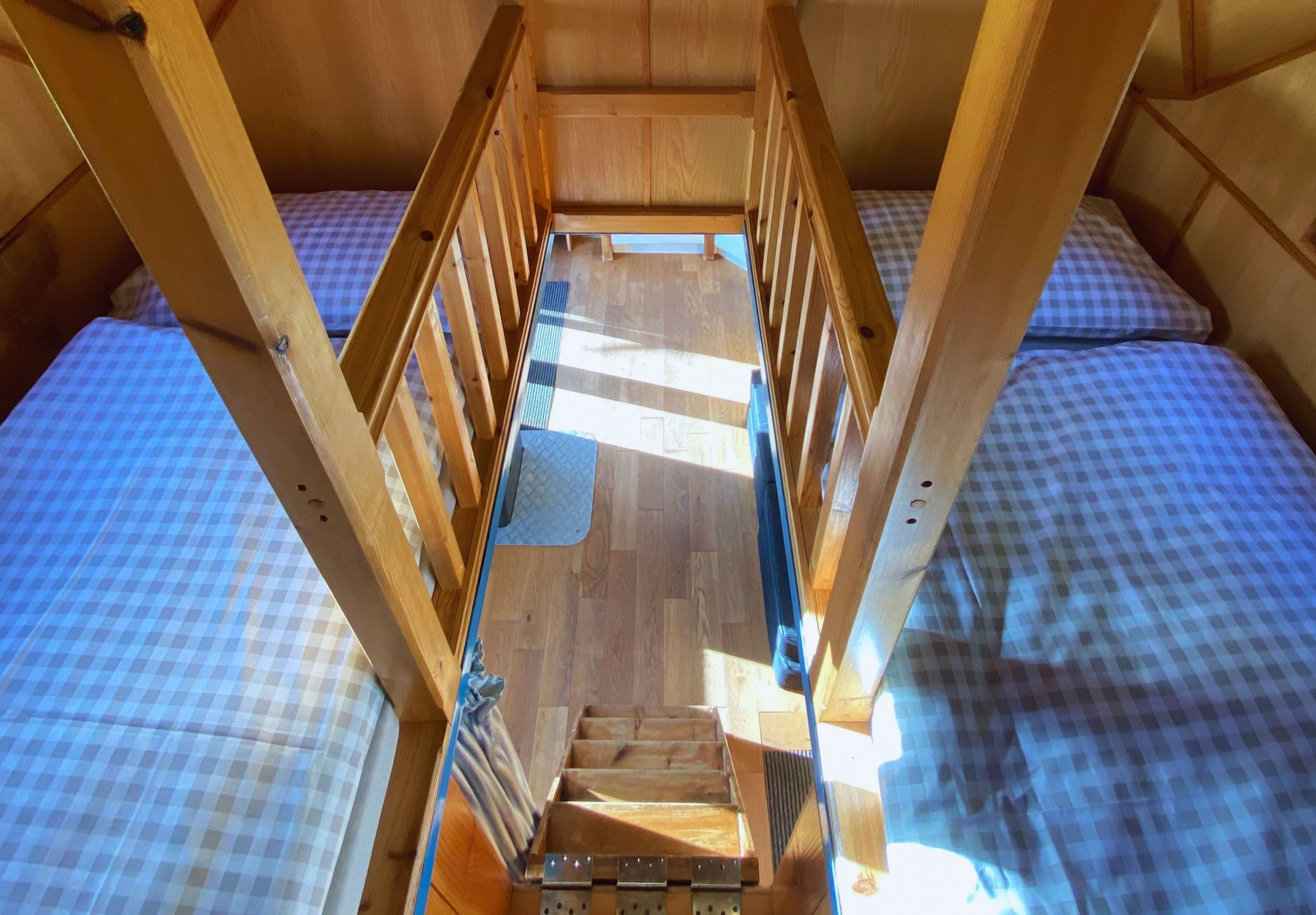A wooden bunk bed with a ladder leading to a lower bunk.