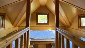 Un intérieur en bois avec un lit superposé, une fenêtre et un escalier.