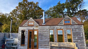 Une cabane en bois avec une cheminée, de grandes fenêtres et une terrasse.