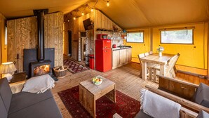 A cozy, wood-furnished room with a fireplace, a dining area, and a kitchen. - Dog friendly glamping accommodation with hot tub in Ripon, Yorkshire (West Tanfield - Ripon)