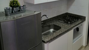 A kitchen with white cabinets, a stainless steel refrigerator, a granite countertop, a gas stove, and a small potted plant. - Near the main park of Salento (Salento)