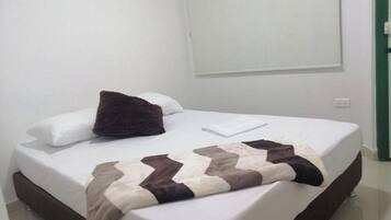 A neatly made bed with a patterned blanket, white pillows, and a dark throw pillow.