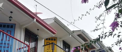 A row of colorful buildings with balconies, each with a different colored door and railing.