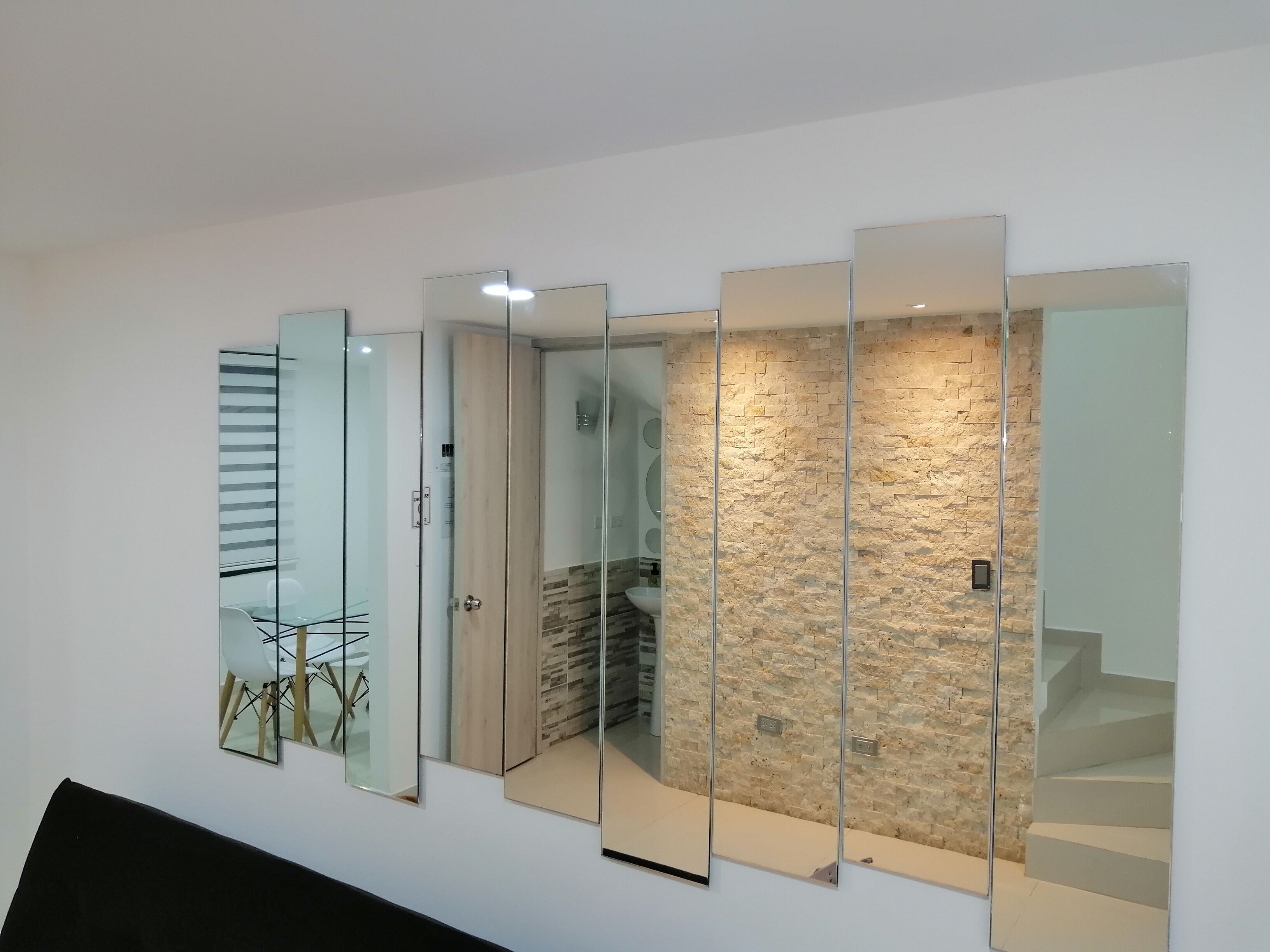 A modern interior with a glass partition wall, a staircase, and a dining area with a table and chairs.