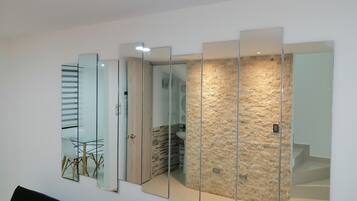 A modern interior with a glass partition wall, a staircase, and a dining area with a table and chairs.