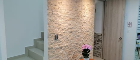 A modern interior with a stone wall, a wooden door, and a staircase.